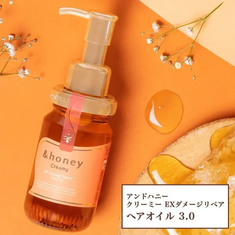 Creamy honey hair oil for damage repair with pump dispenser, golden droplet, and delicate flowers on warm orange background
